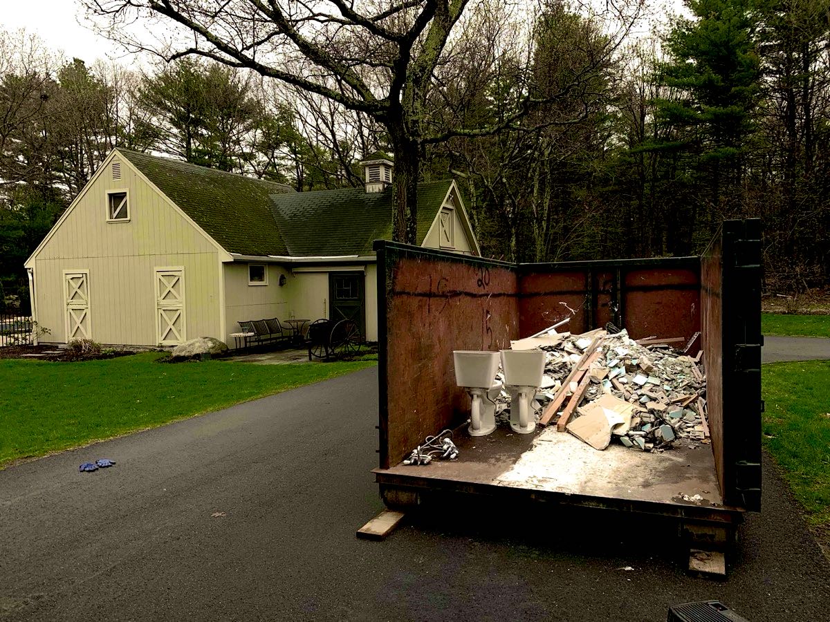 JunkPickup.com roll-off dumpster in a home driveway loaded with debris