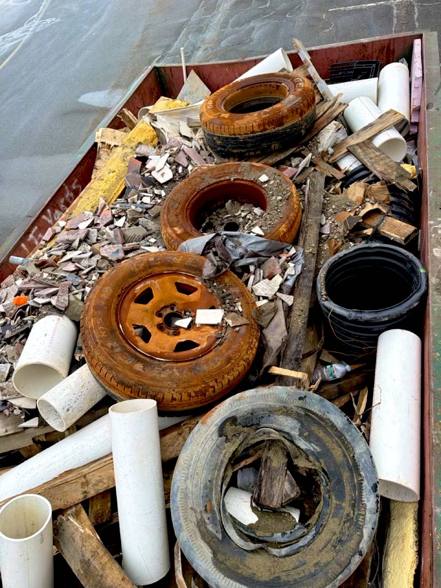 Dumpster load with several old tires mixed in with PVC pipe, tile and wood