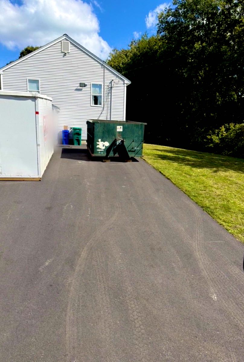JunkPickup.com roll-off dumpster on boards in a home driveway in North Attleborough, MA